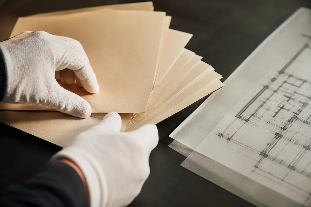 Mains gantées disposant des fiches cartonnées et un plan dessiné sur une table sombre